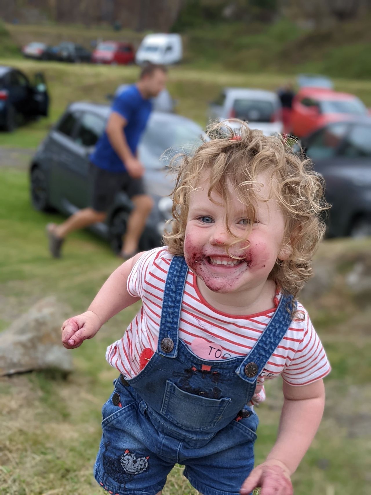 A beaming child with bilberries smeared across their face in Wilton 2 quarry
